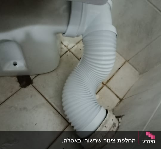 צינור גמיש מחובר לאסלה על רצפת קרמיקה